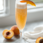 virgin Bellini cocktail in a champagne flute with peach slice garnish and sparkling bubbles