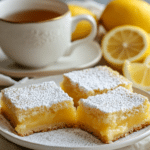 Best Lemon Bars Recipe: How to Make Delicious Lemon Bars at Home 6 Served lemon bars with powdered sugar, fresh lemon slices, and a cup of tea.