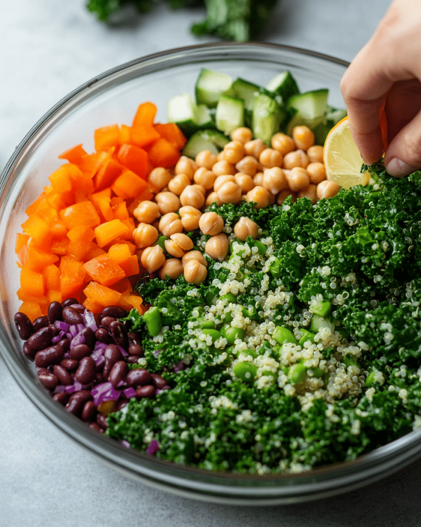 Best High Fiber Salad Recipe: 5 Delicious Ways to Boost Your Fiber Intake 8 Chopped kale, quinoa, beans, vegetables, and lemon garlic dressing being prepared for a high fiber salad.